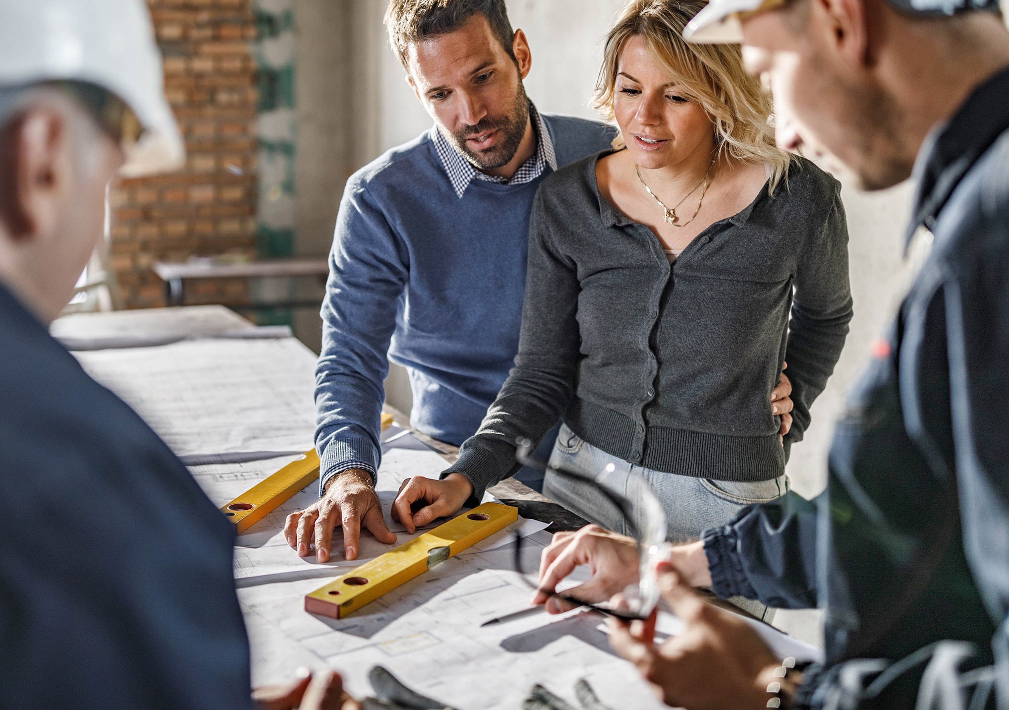Homeowners reviewing blueprints with contractors